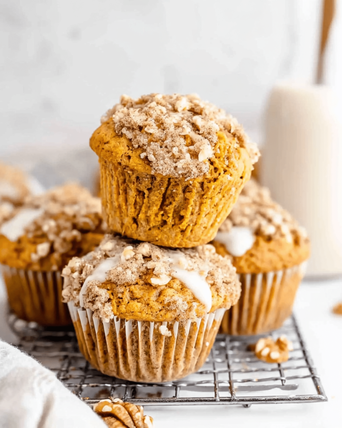 Sweet Potato Muffins topped with crumbly streusel and icing, stacked on a cooling rack.