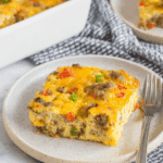A slice of Tater Tot Breakfast Casserole with sausage, cheese, and vegetables served on a ceramic plate.