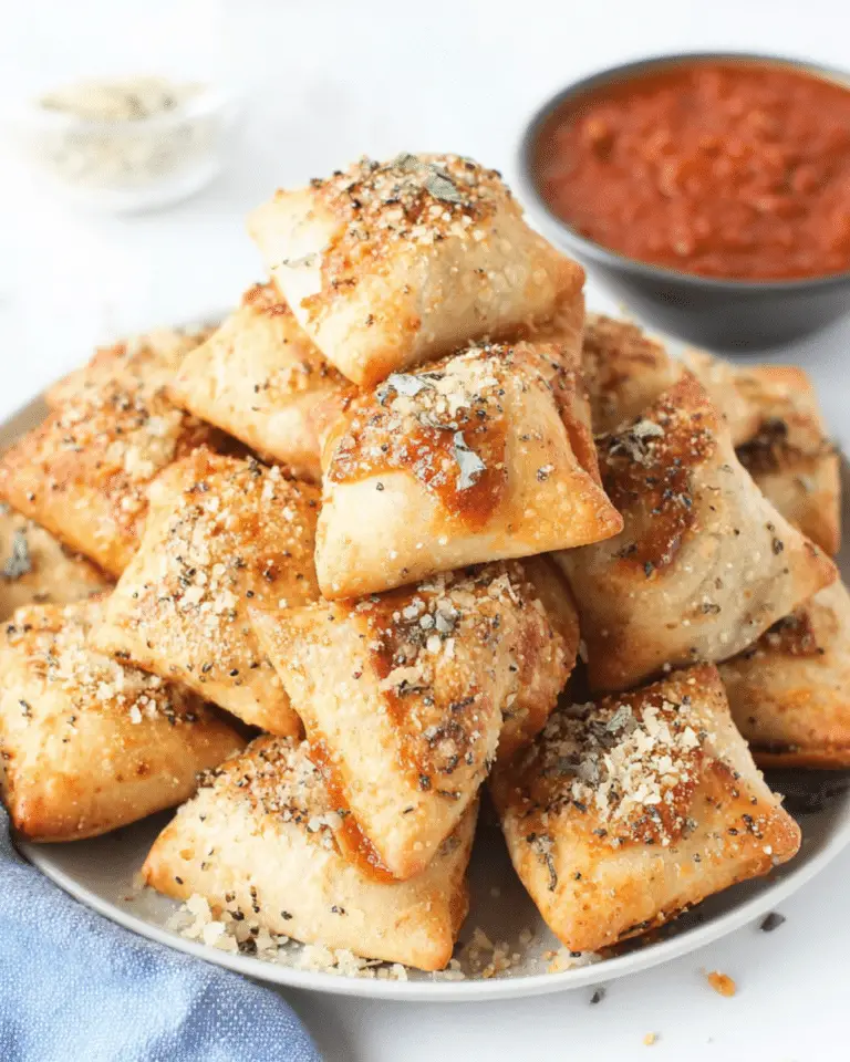A plate stacked with golden, crispy air fryer pizza rolls topped with herbs and parmesan, served with marinara sauce.
