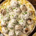 A bowl of Alfredo meatballs served over fettuccine pasta, topped with creamy Alfredo sauce, shredded Parmesan cheese, and fresh parsley.