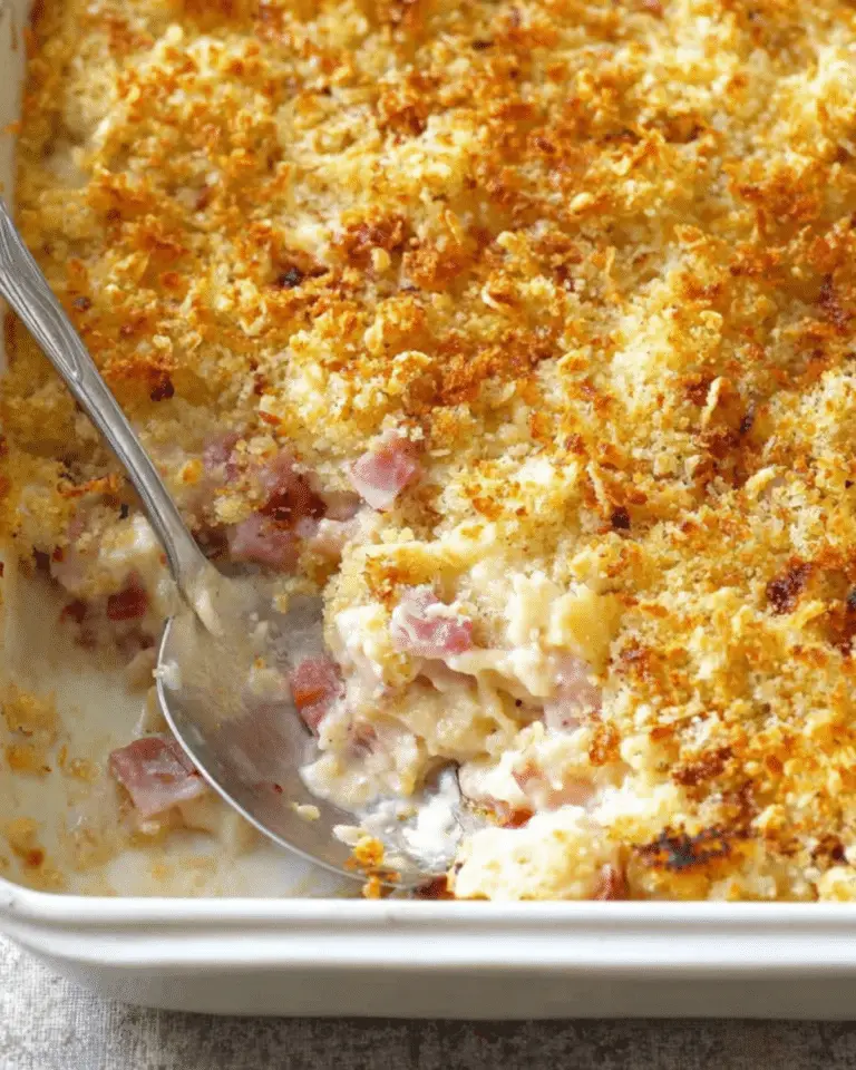 Baked Chicken Cordon Bleu Casserole with a golden breadcrumb topping in a white dish with a serving spoon.