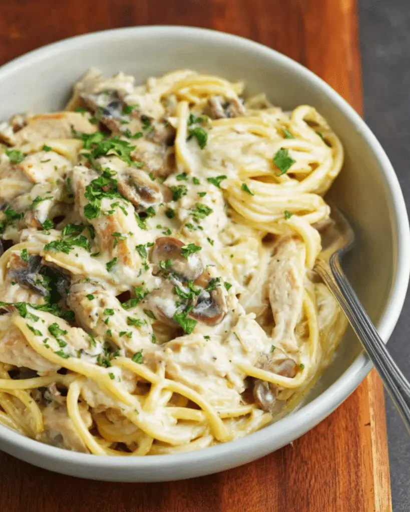 Creamy Chicken Tetrazzini with mushrooms and spaghetti noodles served in a bowl, garnished with fresh parsley.