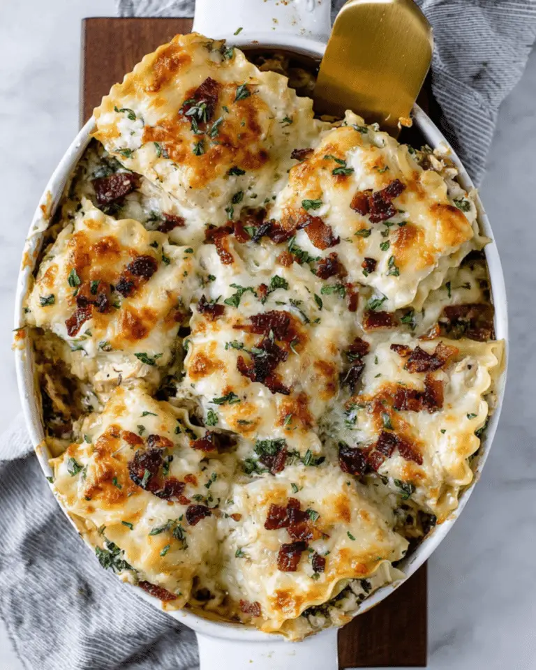 Baked French onion chicken lasagna roll ups topped with melted cheese, crispy bacon, and fresh herbs in a white casserole dish.