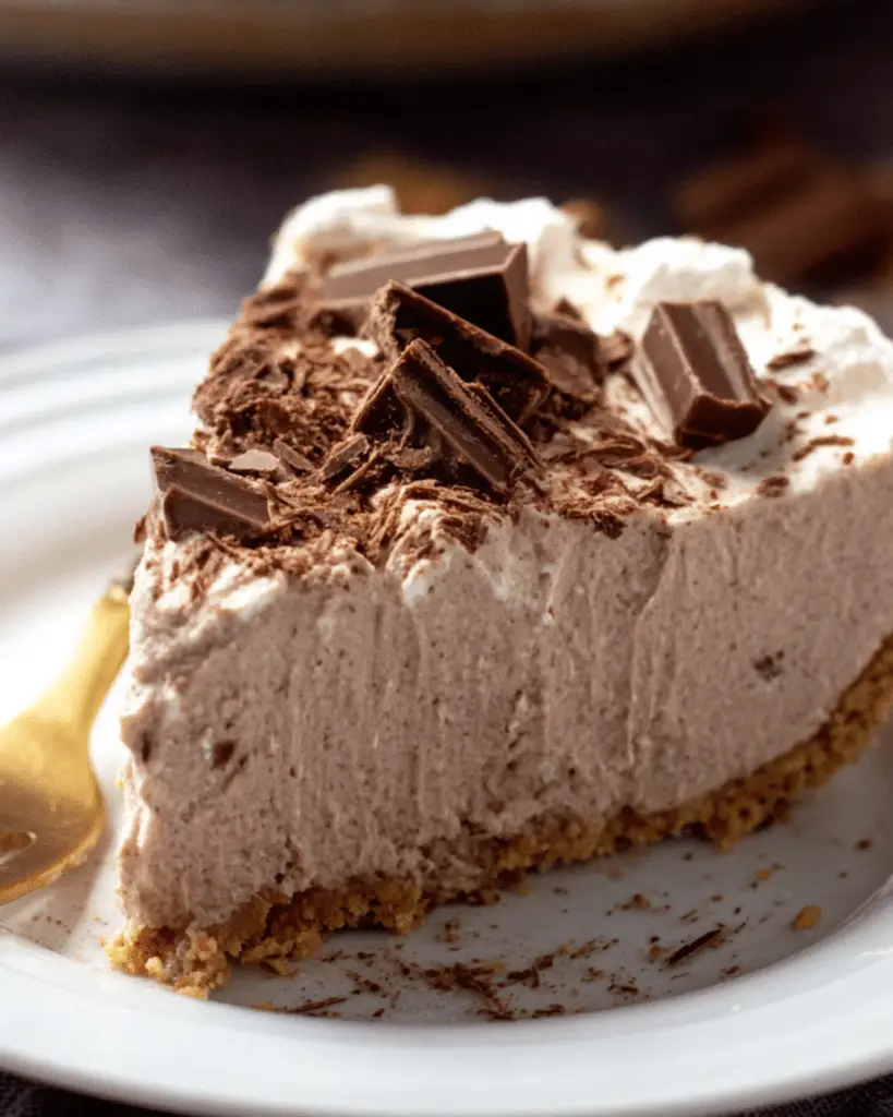 A slice of creamy Hershey Pie topped with chocolate chunks and shavings on a graham cracker crust.