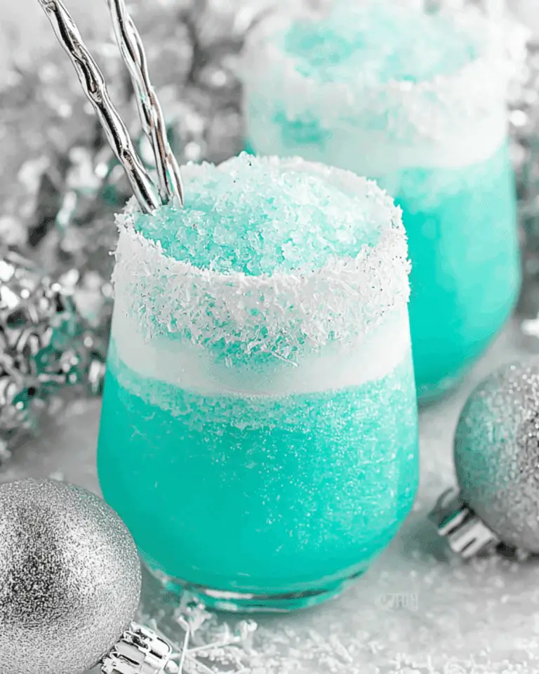 Vibrant blue Jack Frost cocktail in a glass rimmed with shredded coconut, topped with crushed ice, and surrounded by silver holiday decorations.