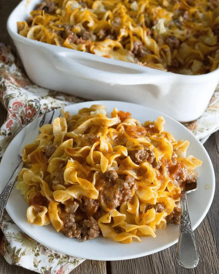 A plate of sour cream noodle bake with ground beef, egg noodles, tomato sauce, and melted cheese.