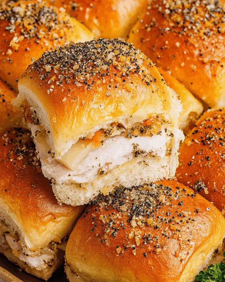 Close-up of freshly baked turkey sliders filled with sliced turkey and melted cheese, topped with a buttery poppy seed seasoning.